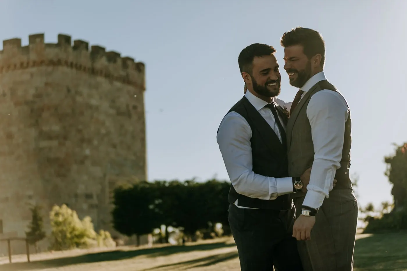 Los dos novios ríen abrazados junto a la torre redonda del Castillo del Buen Amor, Salamanca