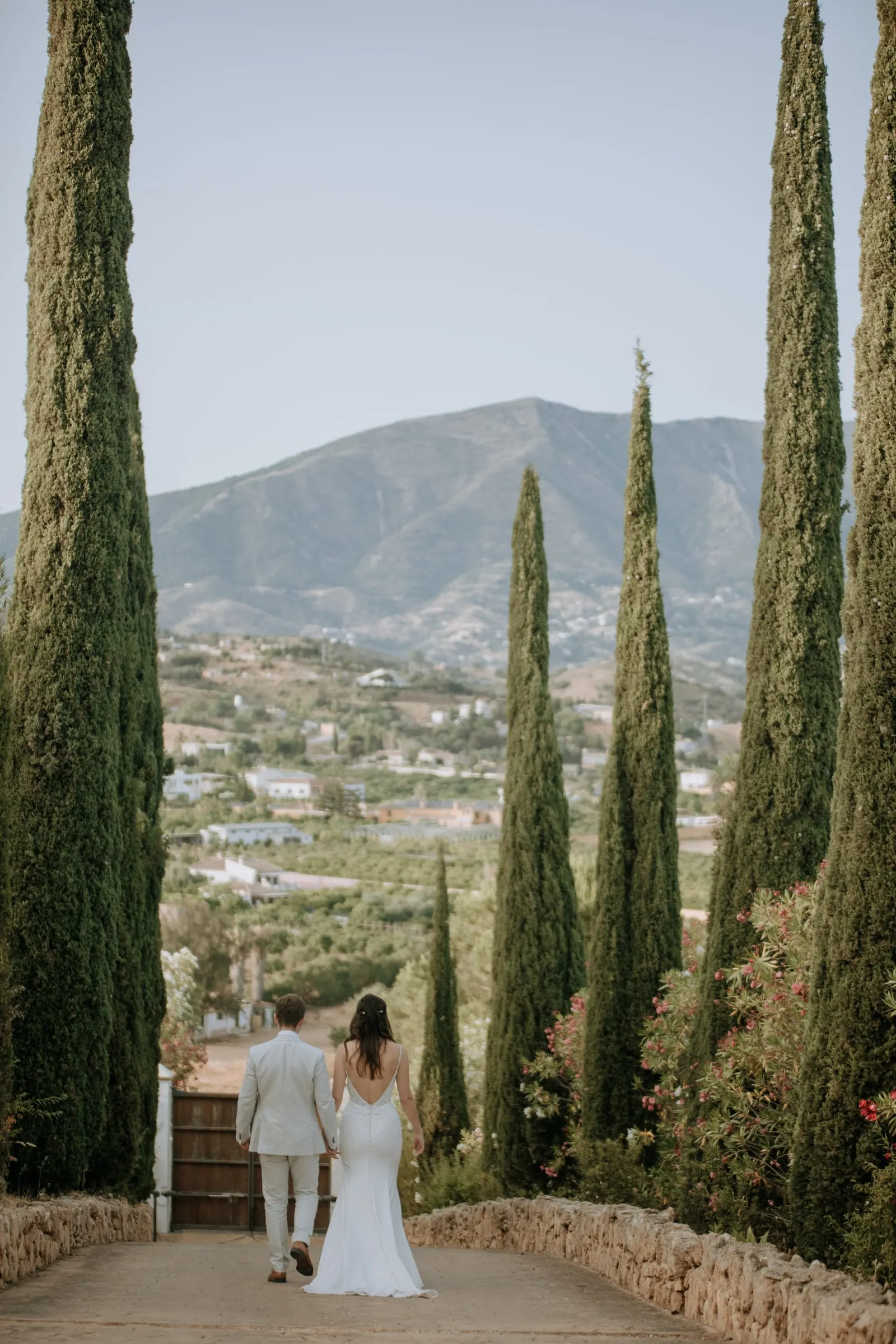 Novios caminando por un camino de cipreses con la sierra al fondo, Costa del Sol