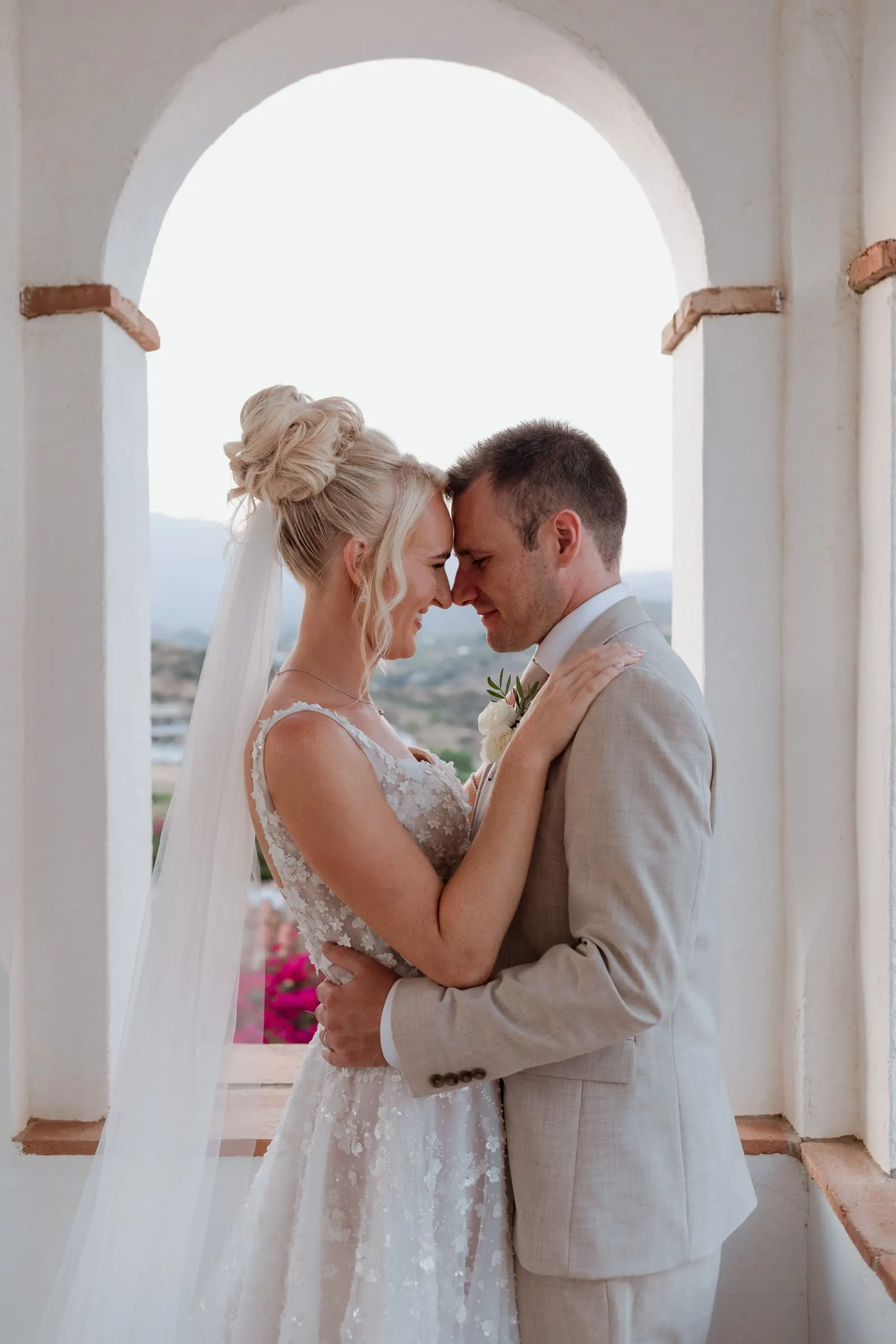 Couple forehead to forehead in a white arch, Mijas