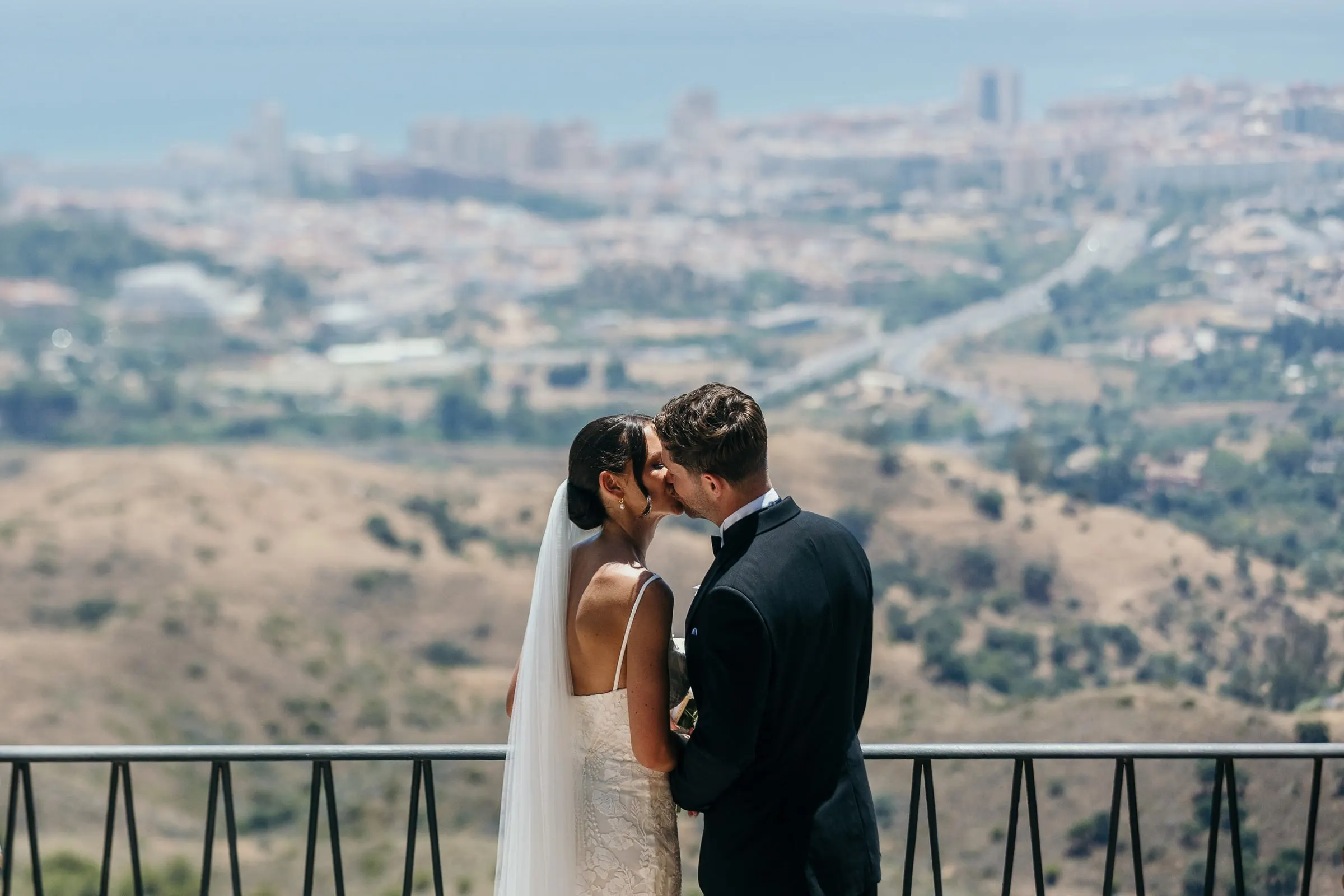 Beso de los novios en un mirador sobre la Costa del Sol en Mijas Pueblo