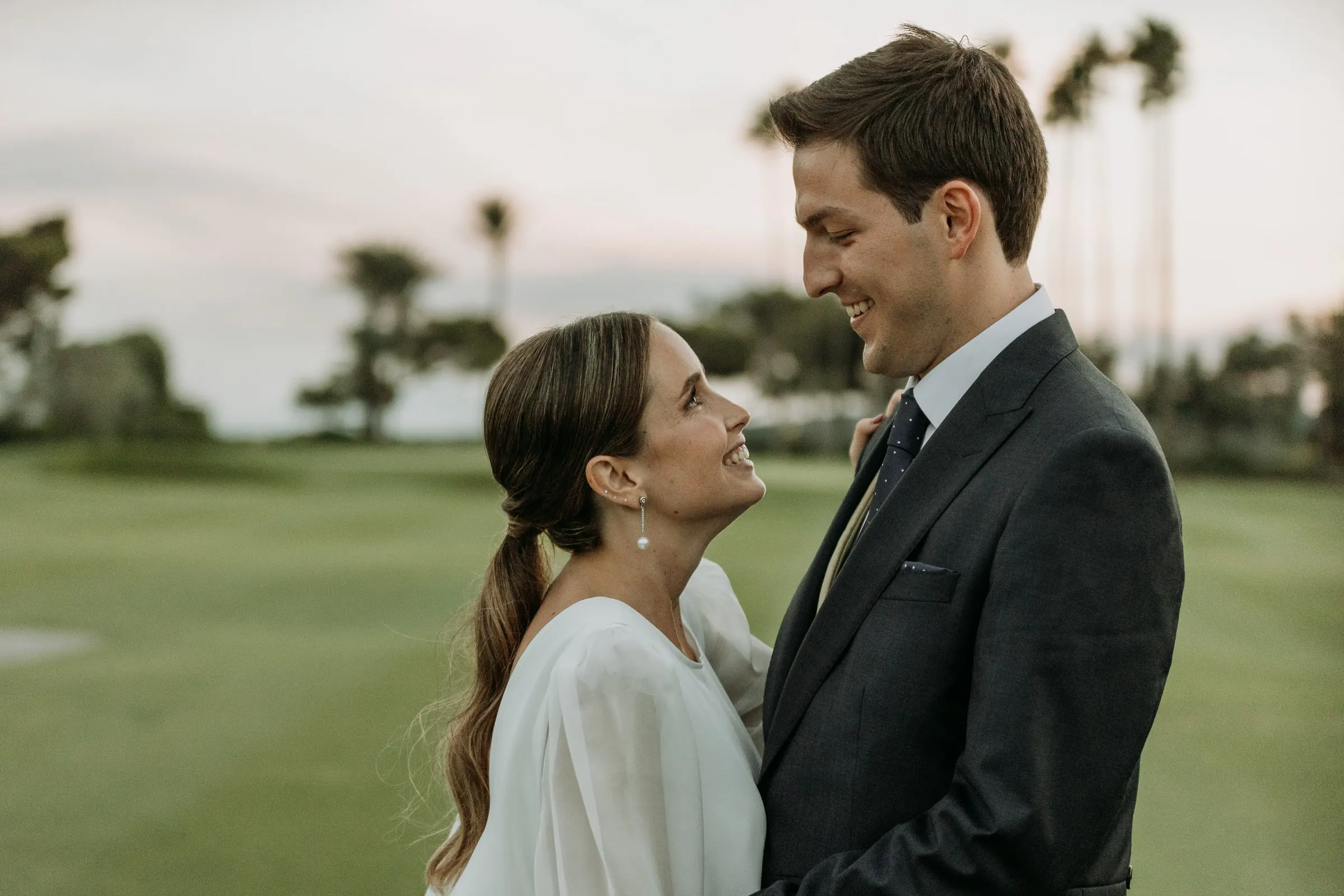 Los novios se miran en el campo de golf al atardecer en Sotogrande