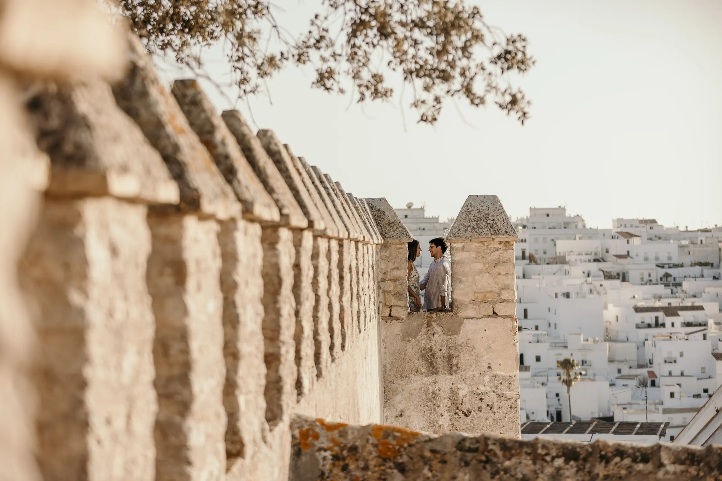 La pareja en las almenas del castillo de Vejer con los tejados blancos del pueblo al fondo